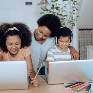 Mother supporting two children in home learning with laptops in a bright and organised home setting.